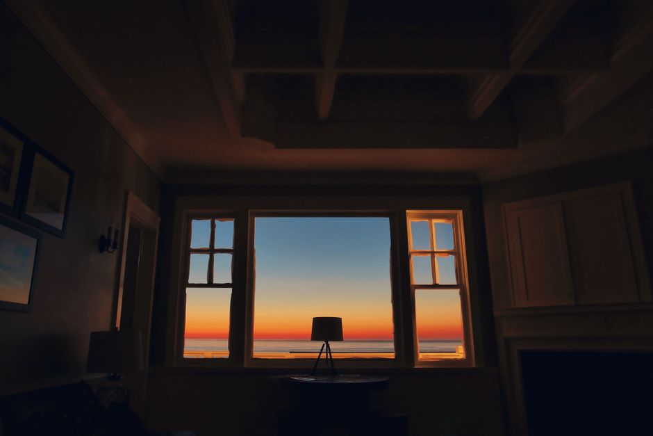 Dark silhouette of a room with a stunning sunset view through a window, creating an artistic interior design ambiance.